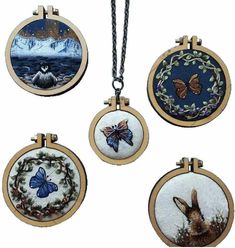 four round pendants with pictures of animals and butterflies hanging from chains on a white background