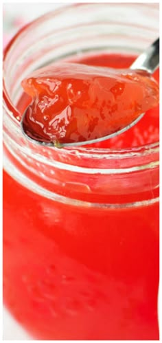 a spoon full of ketchup sitting on top of a jar filled with liquid