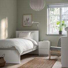 a bedroom with a bed, desk and chair next to a window in the corner