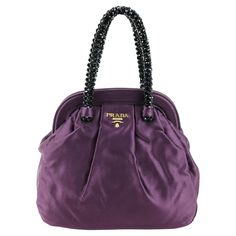 Prada purse in silk color purple, dark stones handle, gold hardware. Condition: Really good. Packing/accessories: Dustbag. Measurements: Width: 20 cm Height: 21 cm Depth: 8 cm Purple Luxury Bag, Luxury Classic Purple Bag, Luxury Designer Purple Bag, Prada Bag Purple, Purple Prada Handbag, Packing Accessories, Prada Purse, Prada Purses, Luxury Purple Shoulder Bag With Silver-tone Hardware