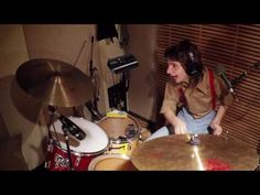 a man sitting in front of a drum set with headphones on and his hands resting on the drums