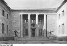 an old black and white photo of the entrance to a building with statues on it