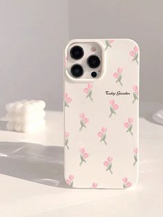 an iphone case with pink flowers on it sitting on a white table next to some cotton balls