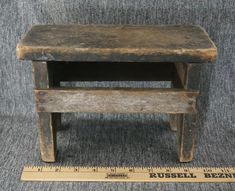 an old wooden table with a measuring tape next to it on a gray couch surface