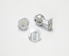 two door knobs and one key lock on a white surface