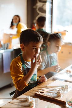 a group of children sitting at a table with doughnuts in front of them