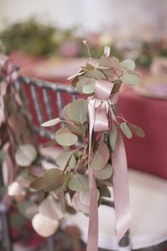 a chair with a pink ribbon tied to it and some flowers in the back ground