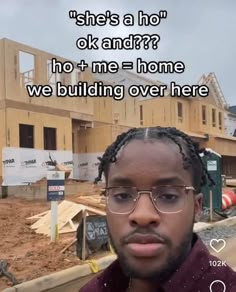 a man with glasses and a red shirt in front of a construction site that is under construction