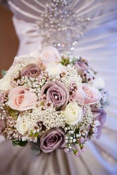 a bridal bouquet with pink and white flowers on the bride's wedding dress