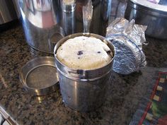 an ice cream cake in a metal bucket on a kitchen counter with pots and pans behind it