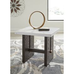 a white marble top end table with a metal ring at the base and a remote control on it