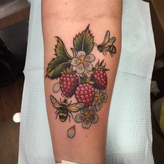 a woman's arm with flowers and berries on it