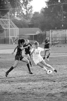 the girls are playing soccer on the field in black and white colors,