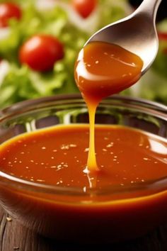 sauce being poured into a glass bowl with salad in the background