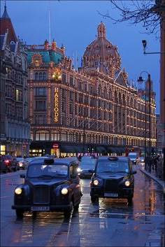 cars driving down the street in front of a building on a rainy day at night