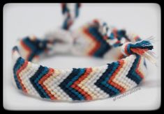 a close up of a bracelet on a white surface with blue, red and orange stripes