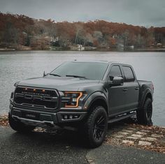 a black truck parked next to a body of water