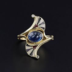 A striking Egyptian Revival ring (circa 1910) with black white and red enamel and a natural blue sapphire at its center.  Two tiny diamonds add a glittery flourish on each point of the ring.  The sapphire cabochon is moderate blue in color and weighs approximately 2.16ct.   The face of the 18k gold ring measures 1 inch tall by 0.4 inches wide, and it is in great condition.  The ring is a size 6.75, but it can be resized free of charge.  It weighs 6.14 grams.  We have many other fantastic offerin Art Deco Enamel Rings For Formal Occasions, Art Deco Enamel Ring As A Gift, Collectible Hallmarked Enamel Ring In Fine Jewelry Style, Art Deco Enamel Ring As Gift, Elegant Open Enamel Ring, Art Deco Diamond Cabochon Rings, Formal Enamel Ring With Gemstone, Art Deco Diamond Rings With Cabochon, Unique Yellow Gold Enamel Ring For Formal Occasions