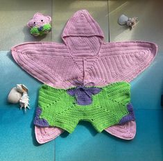 a crocheted baby's diaper is laying on the floor next to toys