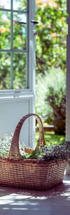 a wicker basket with lavenders in it sitting on the ground next to an open door