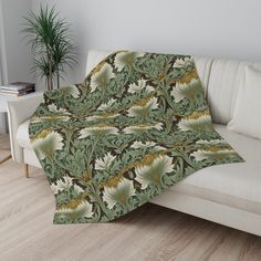 a couch with a blanket on top of it next to a potted palm tree