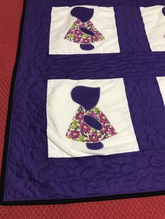 a quilted purple and white wall hanging on a bed