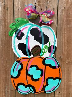 two pumpkins are painted on the side of a wooden fence, one has a cow's head