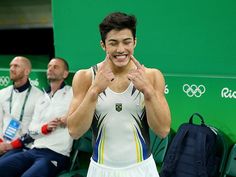 a tennis player is wiping his face in front of the camera while two other men sit behind him