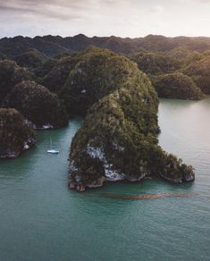 an aerial view of several small islands in the water with trees on both sides and one boat out side