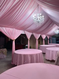 the tables are covered with pink cloths and chandeliers