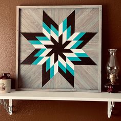 a white shelf with a blue and black star quilt on it next to a candle holder