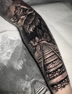 a man's arm with train tracks and mountains on it