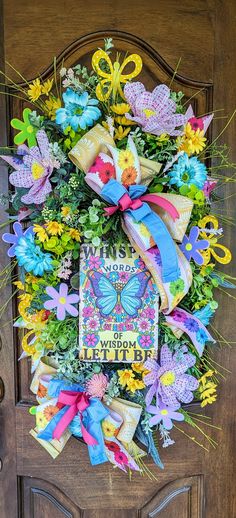 a colorful wreath on the front door of a house with flowers and butterflies around it