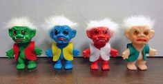 five toy troll dolls lined up in a row on a table, one with white hair and the other red