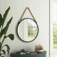 a round mirror hanging on the wall next to a green cabinet and potted plant