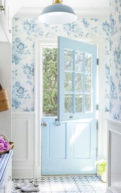 a blue front door in a white and blue room with flowers on the wall next to it