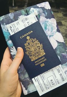 a person holding a canadian passport in front of a flowered background with the word canada on it