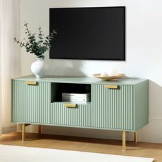 a television is mounted on the wall next to a green cabinet with two gold handles