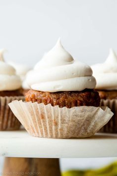 cupcakes with white frosting sitting on a cake plate