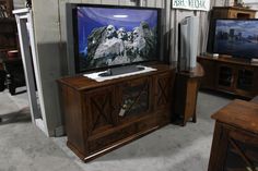 an entertainment center with two televisions on display in the background and other furniture for sale