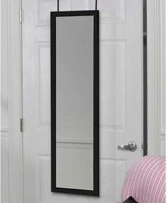 a mirror hanging on the side of a white door next to a pink and black pillow