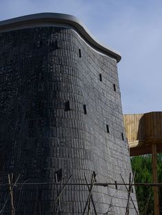 a tall brick tower next to a wooden structure