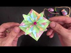 two hands are holding an origami flower