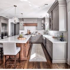 a large kitchen with wooden floors and gray cabinets