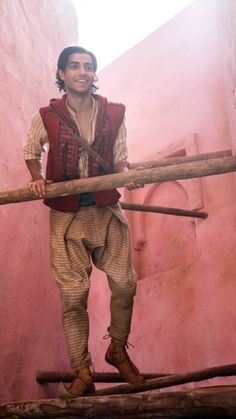 a man is standing on top of a piece of wood with a stick in his hand