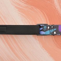 a black belt with purple and blue designs on it's side, against an orange background