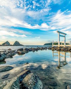 a chair sitting on top of a body of water next to rocks and an ocean