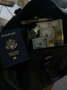 a passport, watch and other items in a black bag on a table next to a laptop