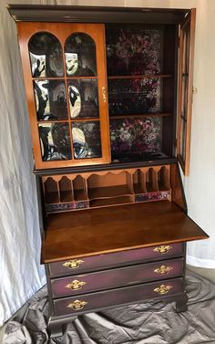 an old fashioned desk with glass doors and drawers