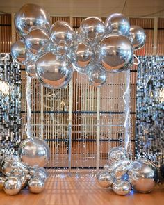 some shiny balloons are hanging from the ceiling in front of a mosaic wall and wooden floor